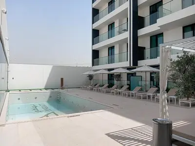 a swimming pool in front of a building at Dusk By Binghatti - Dazzling Studio in JVC in Dubai
