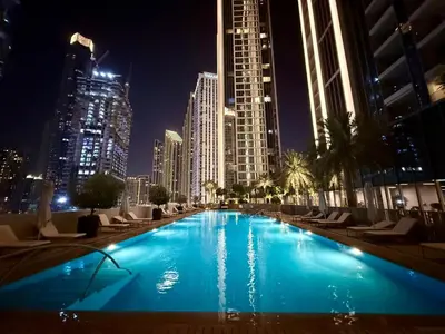 a large swimming pool in a city at night at Serenity Suite Stylish 2BR Pool & Fitness Perks in Dubai