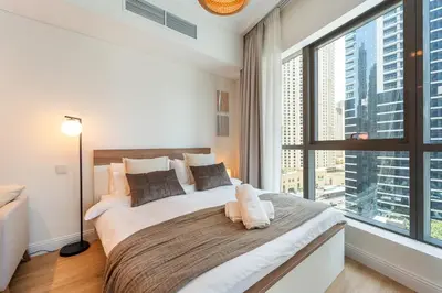 a bedroom with a large bed with a large window at Cozy Marina Studio, Canal View with a Balcony in Dubai