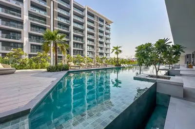 an infinity pool in a building with palm trees at Brand New Studio with Pool View in The Grove by Iman, Dubai Hills in Dubai