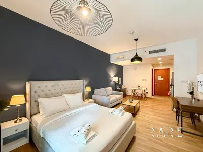 a bedroom with a large bed and a living room at Rare Holiday Homes - Near City Center Ma'eisem - Lake view - Crescent Tower C - R806 - IMPZ in Dubai