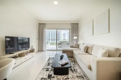 a white living room with a couch and a tv at Airstay - Minimalist 1BR - EMAAR Beachfront - Monthly Offer Available in Dubai