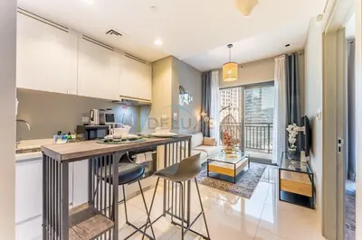 a kitchen and living room with a counter and chairs at Facing the Dubai Water Canal 1BR, Minutes from Metro with Easy Downtown Access, Zada Tower, Business Bay by Deluxe Holiday Homes in Dubai