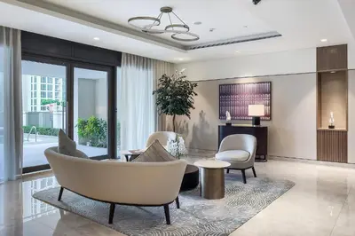 a living room with white chairs and a table at Burj View Stylish 3BR with Maids Room in Act One Tower Downtown in Dubai