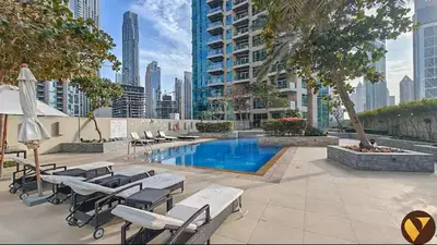 a swimming pool with lounge chairs and a building at Vogue Downtown The Lofts near Burj Khalifa and Dubai Mall, Two Bedroom Apartment with Balcony and City Skyline View, Access to all Amenities in Dubai