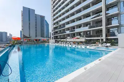 a large swimming pool with chairs and a building at Vogue Downtown Mag 318 near Burj Khalifa and Dubai Mall, Studio Apartment with Balcony, Canal and City View, Access to all Amenities in Dubai