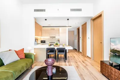 a living room with a green couch and a kitchen at New Luxury 2 Bedroom with Padel Gym Pool Cinema BBQ in Dubai