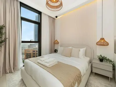 a white bedroom with a large bed and a window at Mahogany 16 - 1BR 4 Guests - Walk to Burj Khalifa in Dubai
