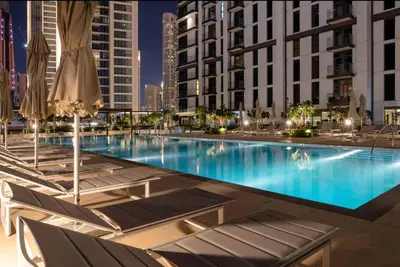 a large swimming pool with chairs and umbrellas at Mahogany 16 - 1BR 4 Guests - Walk to Burj Khalifa in Dubai