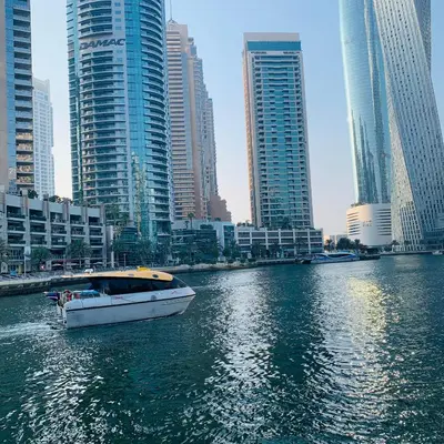 a boat on a river in a city with tall buildings at Modern Studio in Marina in Dubai