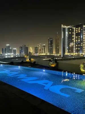 a swimming pool with a city skyline at night at Modern Monastery 1 BR Business Bay in Dubai