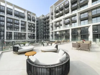 an apartment patio with couches and tables in a building at Modern Studio - Pool, Gym & Padel in Dubai