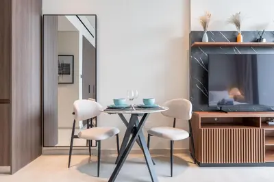 a dining room with a table and chairs and a tv at Modern Studio - Pool, Gym & Padel in Dubai