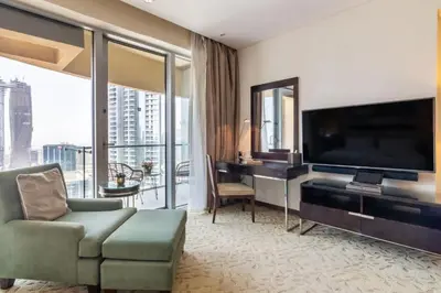 a living room with a large television and a couch and a desk at Luxury Studio Burj Khalifa View Address Dubai Mall in Dubai