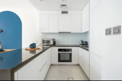 a white kitchen with white cabinets and appliances at 1 Bedroom lagoon by District One in Dubai