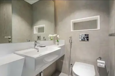 a white bathroom with a sink and a toilet at 1 Bedroom lagoon by District One in Dubai