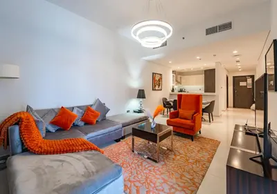 a living room with a blue couch and orange chairs at Chic 2BR in Damac Hills with Golf & Pool View in Dubai
