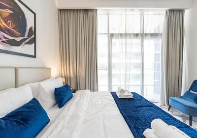 a hotel room with a bed and a blue chair at Chic 2BR in Damac Hills with Golf & Pool View in Dubai