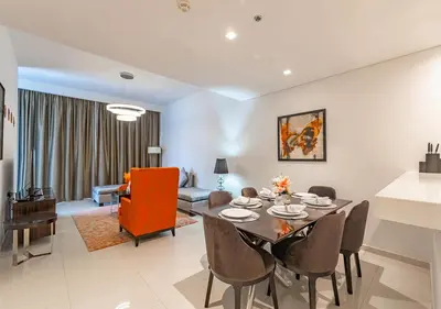 a dining room and living room with a table and chairs at Chic 2BR in Damac Hills with Golf & Pool View in Dubai