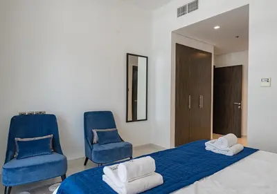 a bedroom with two blue chairs and a bed at Chic 2BR in Damac Hills with Golf & Pool View in Dubai