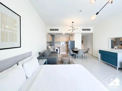 a bedroom with a white bed and a kitchen at City-View Studio in AG Tower l Pool & Gym Access in Dubai