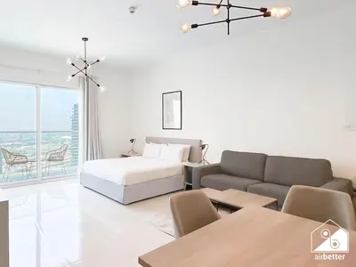 a white living room with a bed and a couch at Skyline Studio Escape l Balcony , Gym & Pool in Dubai