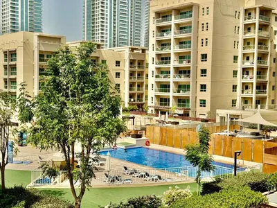 a swimming pool in front of some tall buildings at The Greens very well-lit unit in Dubai