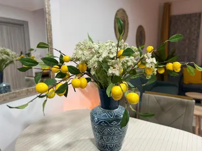 a blue vase with yellow and white flowers on a table at 1 min to ADCB metro New home in Dubai