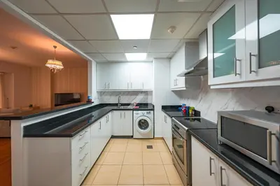 a large kitchen with white cabinets and a washer and dryer at Rimal 4 in Dubai