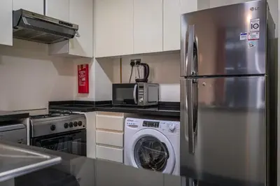 a kitchen with a refrigerator and a washing machine at 1BHK Retreat Peaceful & Bright in Dubai