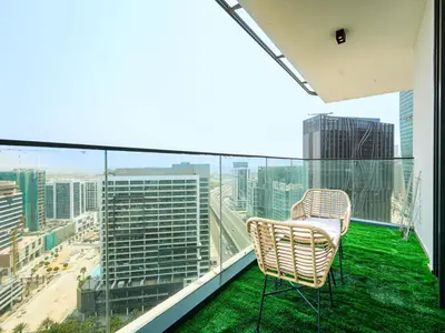 a chair on a balcony with a view of a city at Luxury Smart 1BR -High Floor Business Bay Views in Dubai
