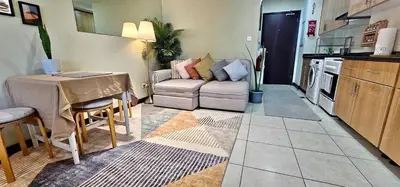 a living room with a couch and a table in a kitchen at Higuests - Close to METRO Charming Studio with Lake Views in Dubai