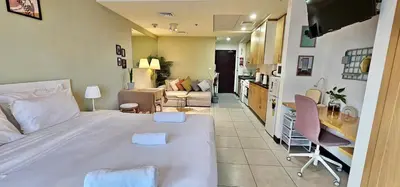 a bedroom with a large white bed and a living room at Higuests - Close to METRO Charming Studio with Lake Views in Dubai