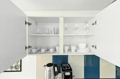 a kitchen with a coffee maker and glasses on shelves at 1BR at Ocean Heights Next to Tram Station in Dubai
