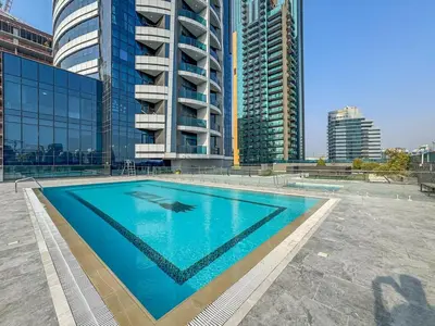 a swimming pool in front of some tall buildings at Modern Studio - near Dubai Hills Mall - Pool & Gym in Dubai