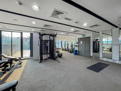 a gym with cardio equipment in a building with windows at Modern Studio - near Dubai Hills Mall - Pool & Gym in Dubai