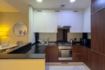a kitchen with white cabinets and a sink and a table at Elegant 1BR with Canal Views in Business Bay in Dubai