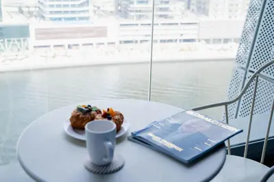 a table with a book and a cup and pastry on it at Spacious 1BR in Business Bay l Pool, Gym & Parking in Dubai