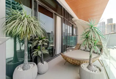a balcony with two palm trees and a chair at Oxford Luxury 1 bedroom & study in Dubai