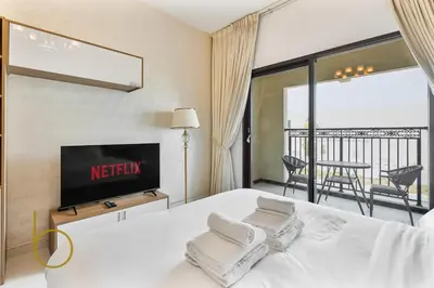 a hotel room with a bed with a tv and a balcony at Bookable- Studio Resortz By Danube with Balcony in Dubai