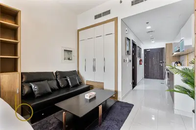 a living room with a black couch and a table at Bookable- Studio Resortz By Danube with Balcony in Dubai