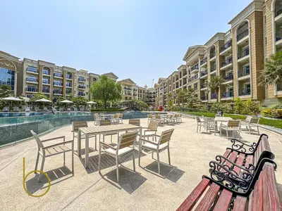 a patio with tables and chairs in front of a building at Bookable- Studio Resortz By Danube with Balcony in Dubai