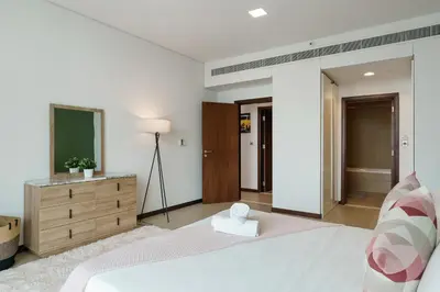 a bedroom with a large white bed and a dresser at Gorgeous 2BR in DIFC close to Metro & Dubai Mall in Dubai