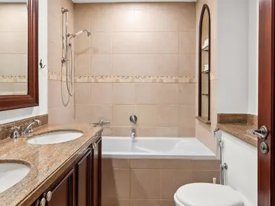 a bathroom with two sinks and a tub and a toilet at Spacious 2BR Steps from Downtown in Dubai