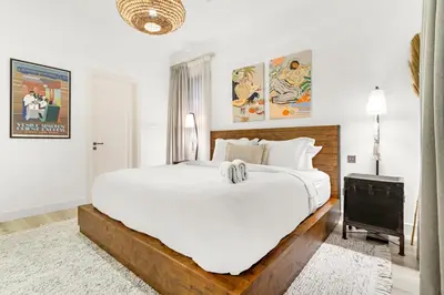 a white bedroom with a large bed and a tv at Dubai 2BR Pool View, Near Burj Khalifa, Canal & Attractions in Dubai