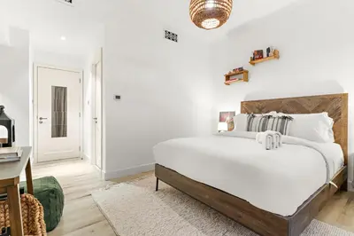 a white bedroom with a large bed and a desk at Dubai 2BR Pool View, Near Burj Khalifa, Canal & Attractions in Dubai