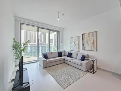 a living room with a couch and a large window at Deluxe 1-Bedroom in The Grand - Waterfront and Skyline Views in Dubai