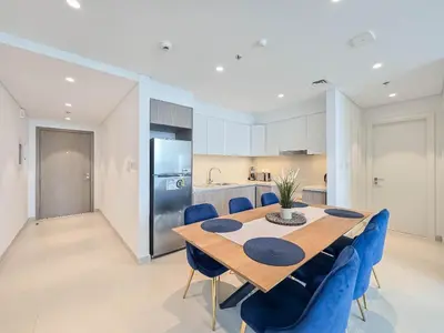 a kitchen with a wooden table and blue chairs at Deluxe 1-Bedroom in The Grand - Waterfront and Skyline Views in Dubai