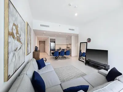 a living room with a couch and a tv at Deluxe 1-Bedroom in The Grand - Waterfront and Skyline Views in Dubai