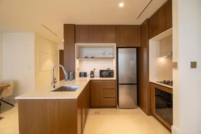 a kitchen with wooden cabinets and a stainless steel refrigerator at Lux and Spacious 1 Bed with Beach in Dubai